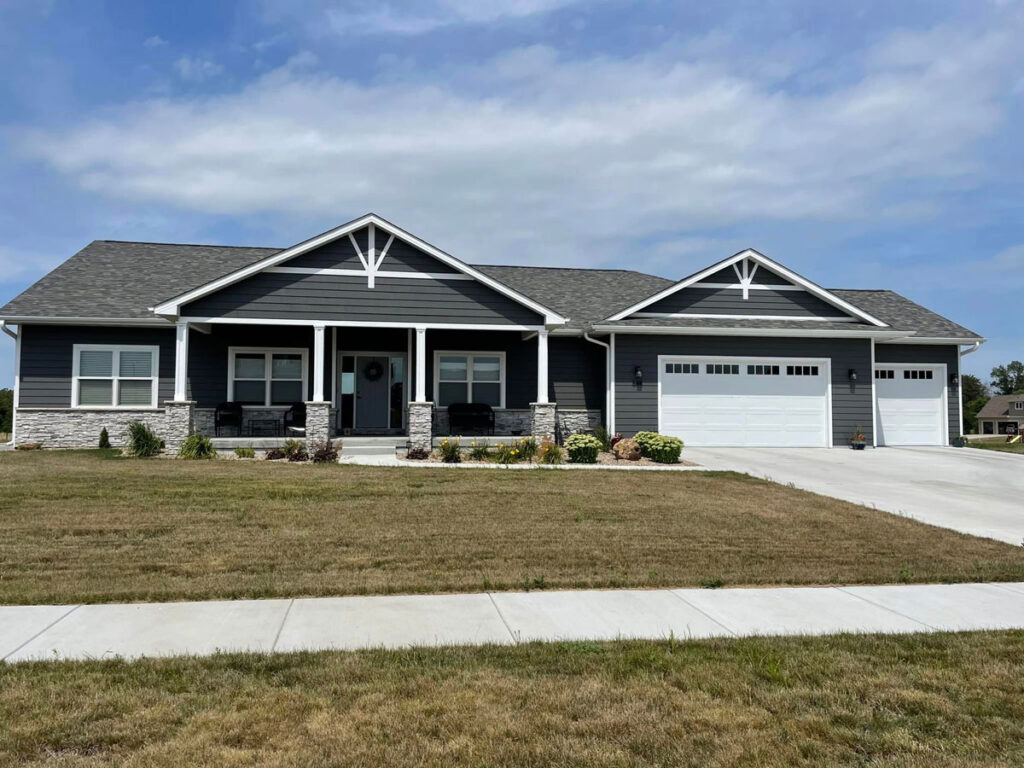 A dark blue-gray house with light gray brickwork and white accents.